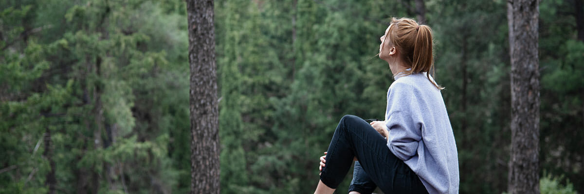 Woman sits among forest of trees in Seattle | Pacific Arboriculture